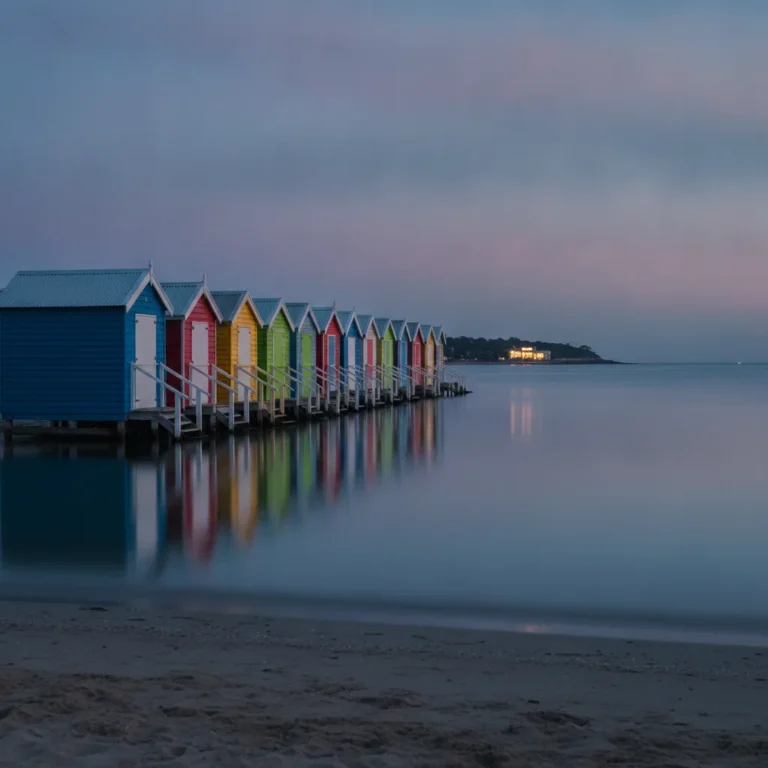Colourful bathing boxes on a Melbourne bayside beach under a blue dusk sky