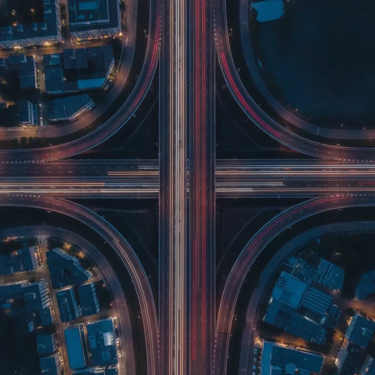 Aerial view of two roads merging at dusk with red and white light trails