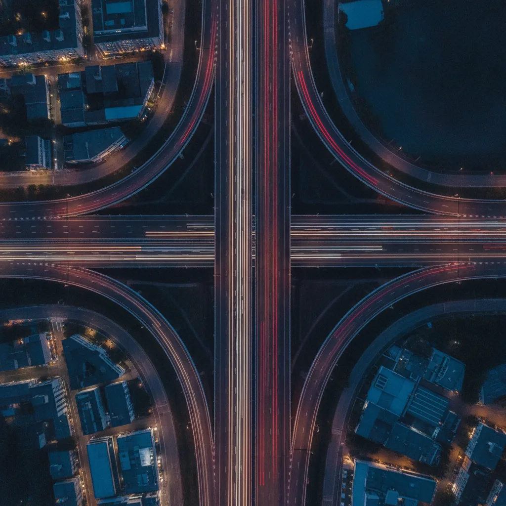 Aerial view of two roads merging at dusk with red and white light trails